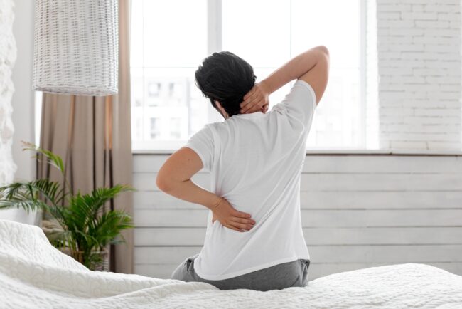 Unrecognizable,Guy,Suffering,From,Back,Pain,In,Bedroom,,Waking,Up